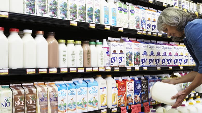 A woman holding a jug of milk at the grocery store