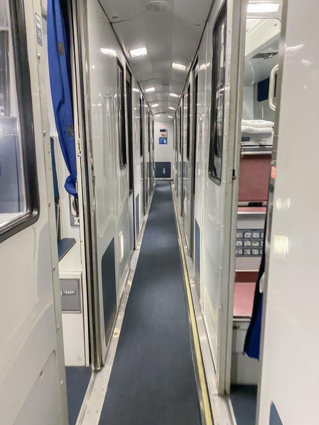 A narrow hallway of roomettes on an Amtrak