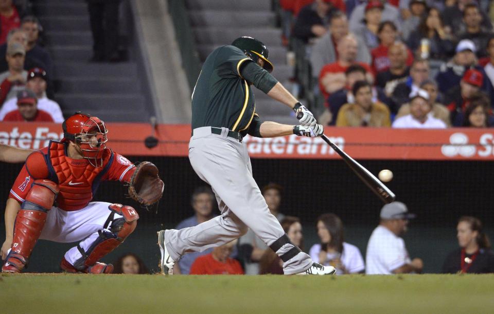 Oakland Athletics' Brandon Moss, right, hits a three-run home run as Los Angeles Angels catcher Chris Iannetta watches during the fourth inning of a baseball game, Wednesday, April 16, 2014, in Anaheim, Calif. (AP Photo/Mark J. Terrill)