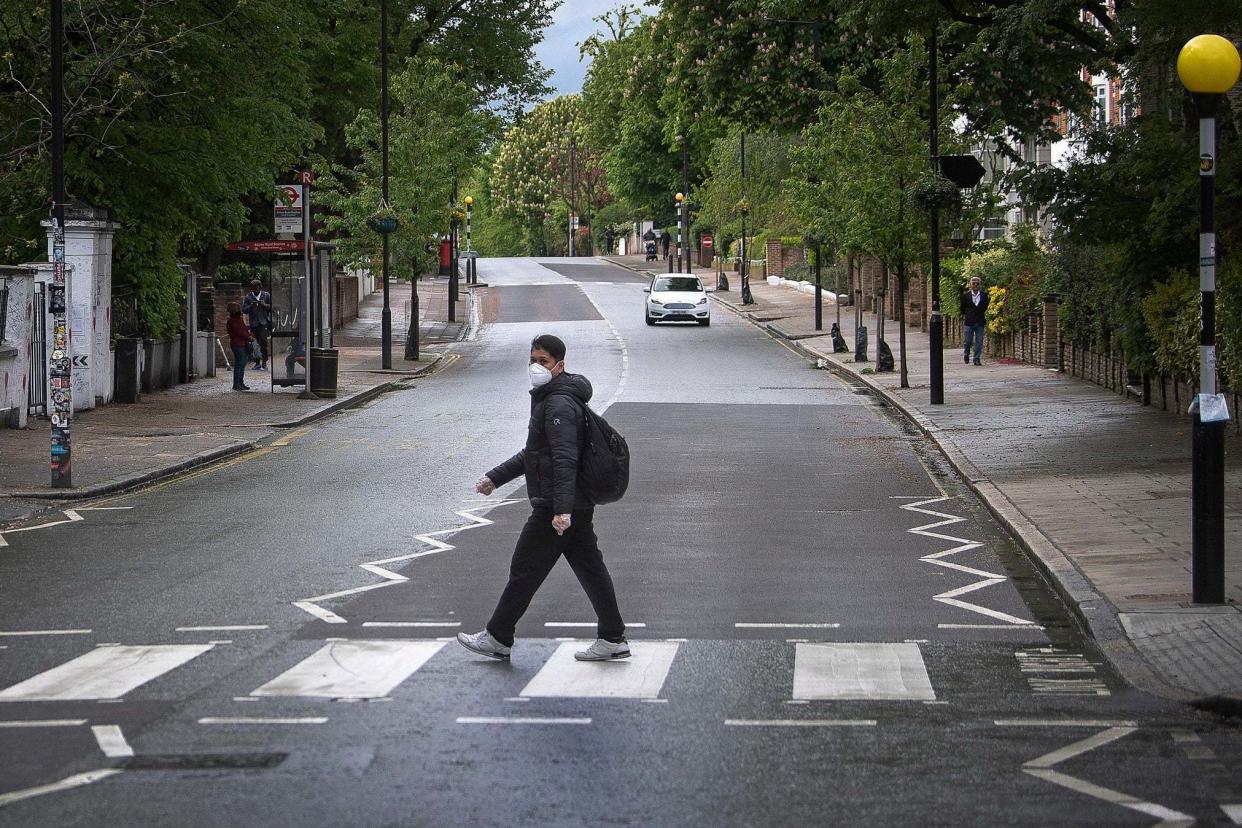 A man wearing a face mask crosses the famous zebra crossing outside the Abbey Road studios: PA
