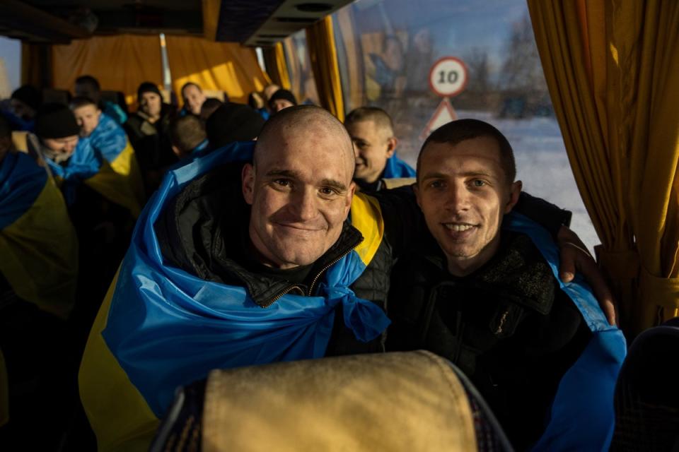 Recently swapped Ukrainian prisoners of war covered in national flags sit in a bus after a prisoner exchange on the Ukrainian Russian border (AP)