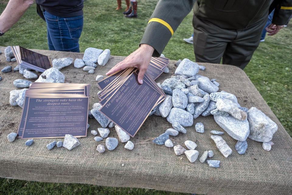 Pieces of stone chipped from memorial benches are taken by people during the dedication of the Borderline Healing Garden at Conejo Creek Park in Thousand Oaks, Calif., Thursday, Nov. 7, 2019. The dedication marked the anniversary of a fatal mass shooting at a country-western bar a year earlier. (Hans Gutknecht/The Orange County Register via AP)