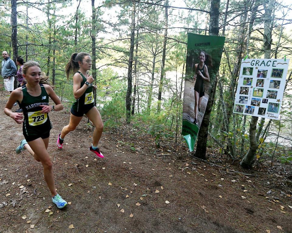 Marshfield's Grace Ciocca runs past her sign with Charlotte Perrault during the first lap of their meet against Hingham at Marshfield High on Wednesday, Oct. 12, 2022. Marshfield girls would win 19-39 while Marshfield boys won 19-44.