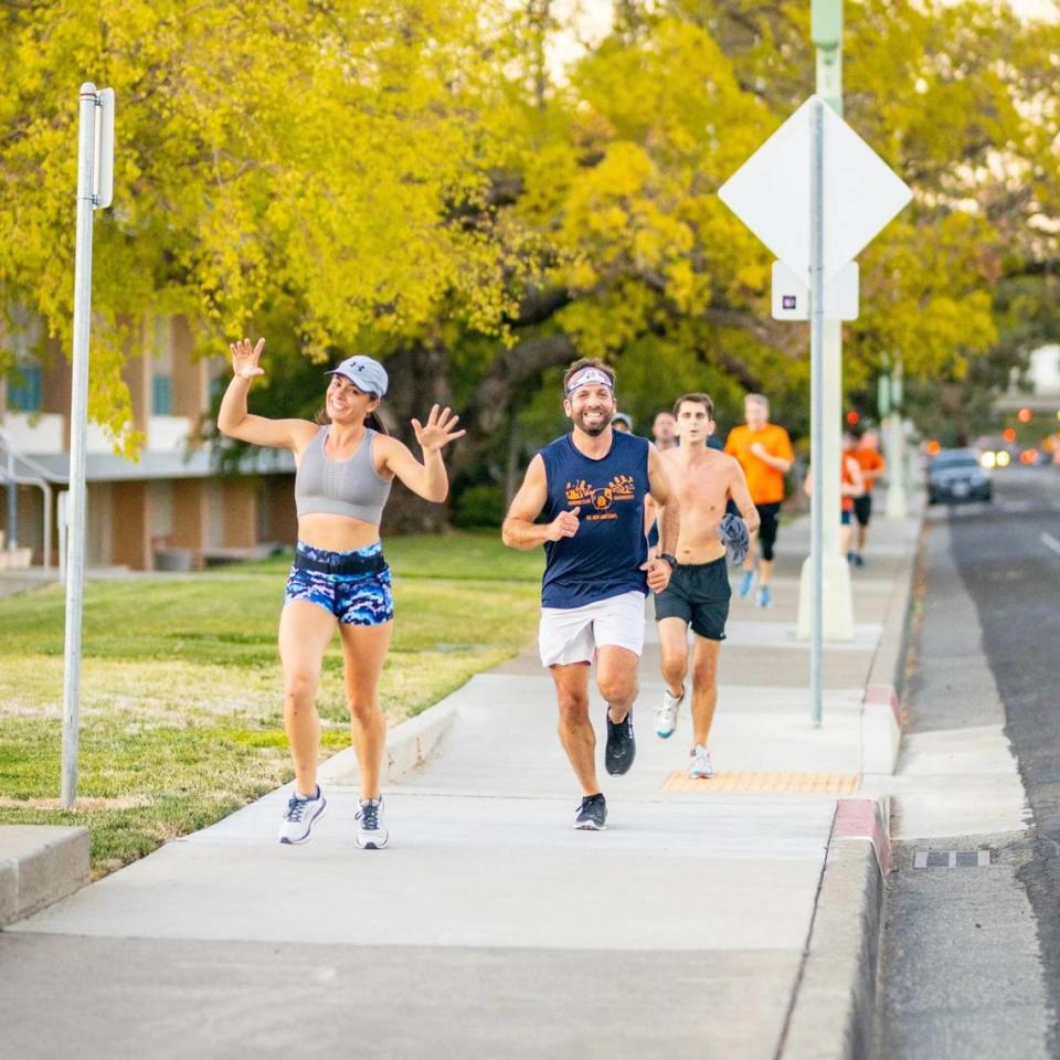 Sara Wolf, left, and Greg Shirey, right, members of Sloppy Moose Running Club, jog down a tree-lined street on Sept. 30, 2021, in the Sacramento region.