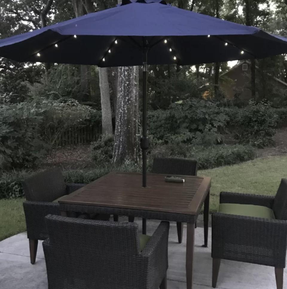 Reviewer's photo of the blue umbrella open at nighttime with the LED lights lit up