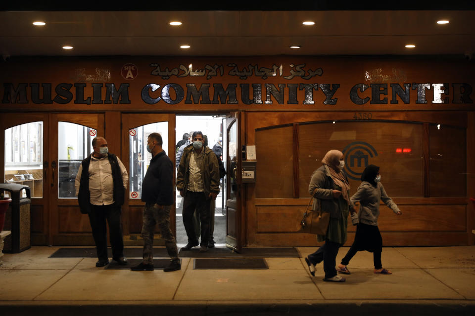 Muslims exit Chicago's Muslim Community Center after an evening prayer called "tarawih" as others pass by during the first evening of the holy fasting month of Ramadan at Chicago's Muslim Community Center on Monday, April 12, 2021. (AP Photo/Shafkat Anowar)