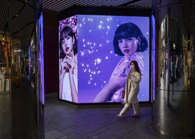 BEIJING, CHINA - DECEMBER 09: A woman walks by an ad for a cosmetic company as part of a display at a shopping mall on December 9, 2020 in Beijing, China. The revival of consumer consumption is expected to continue to boost China's economy, which is already showing strong signs of post-pandemic recovery and providing a bright spot for global brands and retailers. (Photo by Kevin Frayer/Getty Images)