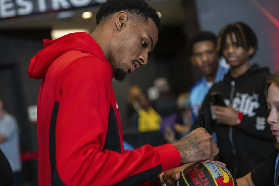 Atlanta Hawks guard Dejounte Murray (5) autographs a ball for a fan after the preseason NBA basketball game against the New Orleans Pelicans, Saturday, Oct. 14, 2023, in College Park, Ga. (AP Photo/Hakim Wright Sr.)