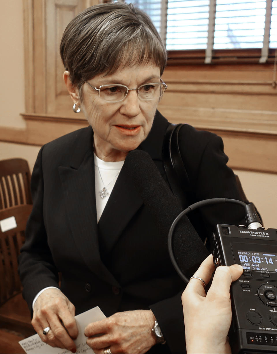 In this photo from Tuesday, Dec. 4, 2018, Kansas Gov.-elect Laura Kelly answer questions from reporters during a break in a legislative meeting at the Statehouse in Topeka, Kan. Kelly, a Democrat, races a push in the Republican-controlled Legislature to cut state income taxes to offset a revenue windfall caused by changes in federal tax laws at the end of 2017. (AP Photo/John Hanna)