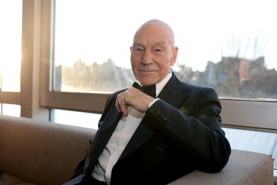 Sir Patrick Stewart, wearing a tuxedo, leans back on a sofa and smiles softly as he attends the EE BAFTA Film Awards 2023 at The Royal Festival Hall on February 19, 2023