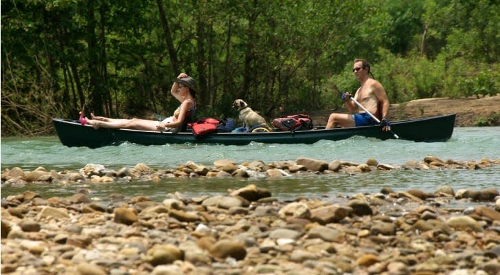 A couple with their dog in a canoe floating down an Arkansas river.