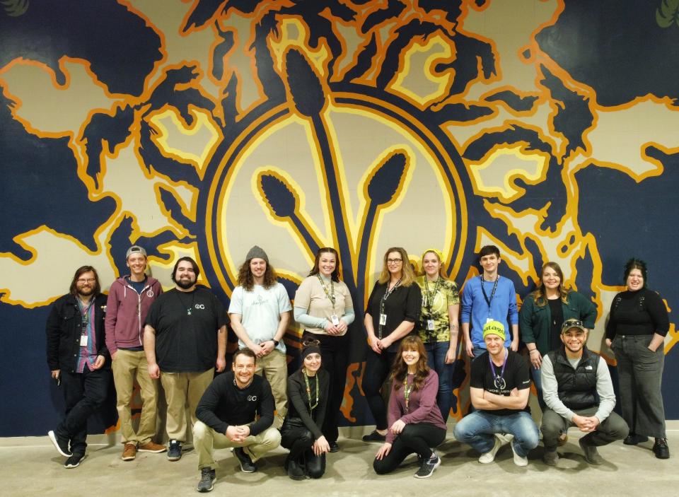 Employees of Dunegrass in front of a mural that is located in the area next to the store on South Otsego Avenue in Gaylord.