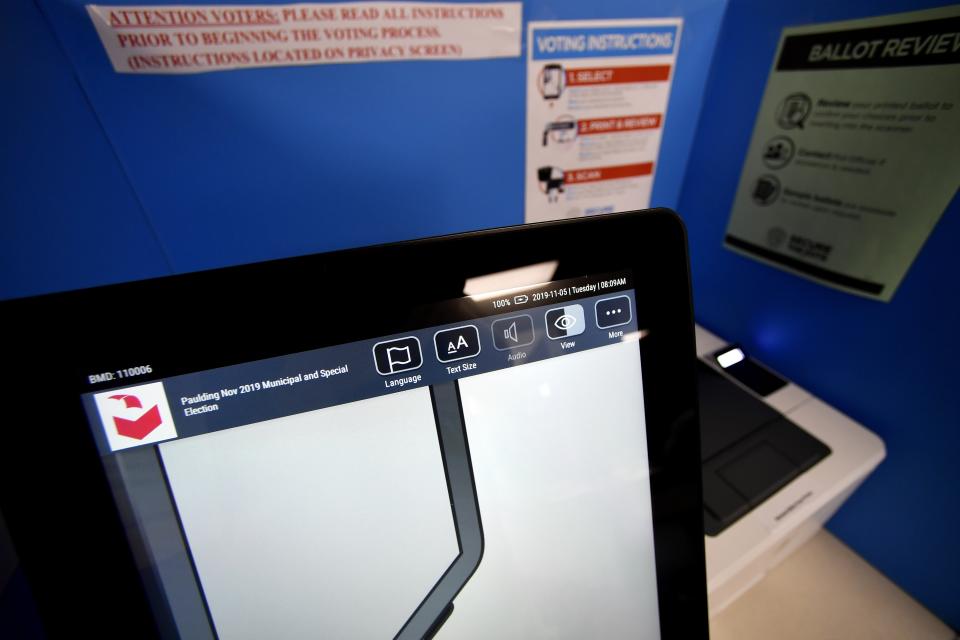 In this Tuesday, Nov. 5, 2019 photo, a touchscreen voting machine and printer are seen in a voting booth, in Paulding, Ga. Election integrity activists want a federal judge to order Georgia to stop using its current election system, saying it's vulnerable to attack and has operational issues that could cost voters their right to cast a vote and have it accurately counted.(AP Photo/Mike Stewart)