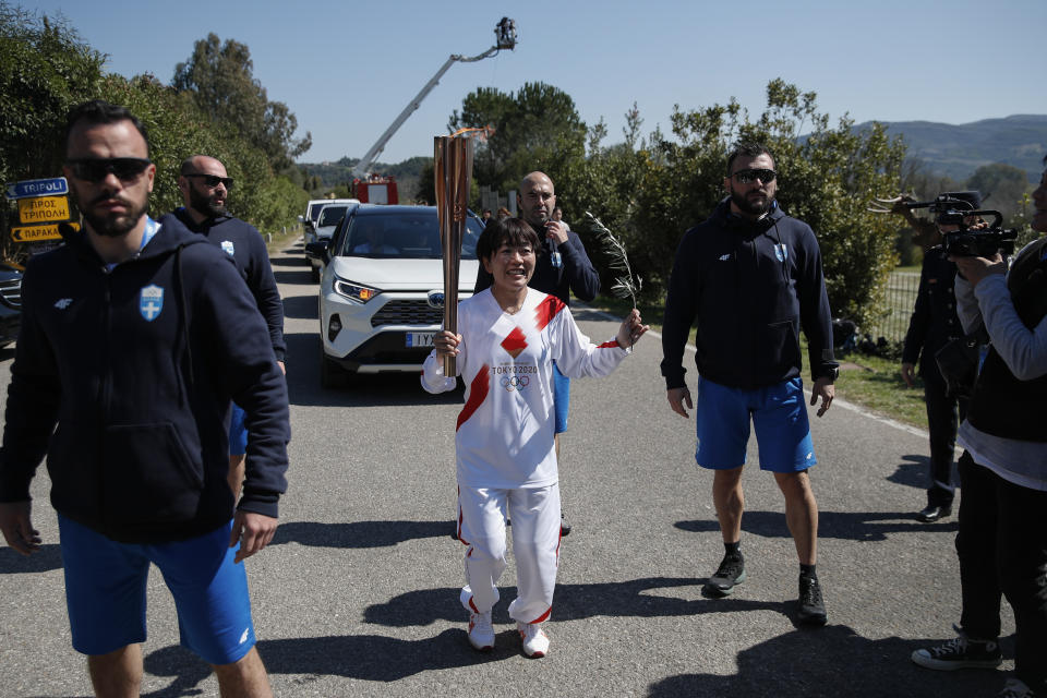 Japanese Olympic marathon champion, Mizuki Noguch, center, the second torchbearer, holds the torch of the 2020 Tokyo Olympic Games following the flame lighting ceremony at the closed Ancient Olympia site, birthplace of the ancient Olympics in southern Greece, Thursday, March 12, 2020. Greek Olympic officials are holding a pared-down flame-lighting ceremony for the Tokyo Games due to concerns over the spread of the coronavirus. Both Wednesday's dress rehearsal and Thursday's lighting ceremony are closed to the public, while organizers have slashed the number of officials from the International Olympic Committee and the Tokyo Organizing Committee, as well as journalists at the flame-lighting. (AP Photo/Thanassis Stavrakis)