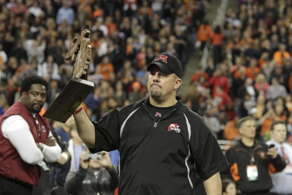 Muskegon coach Shane Fairfield accepts the runner-up trophy after its MHSAA Division 2 championship game loss against Birmingham Brother Rice, 38-21, on Nov. 29, 2013 at Ford Field in Detroit.