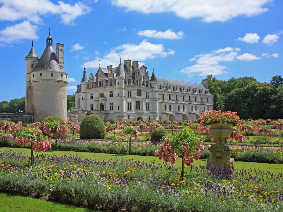 Chateau de Chenonceau surrounded by green grass and flowers in Loire Valley, France.