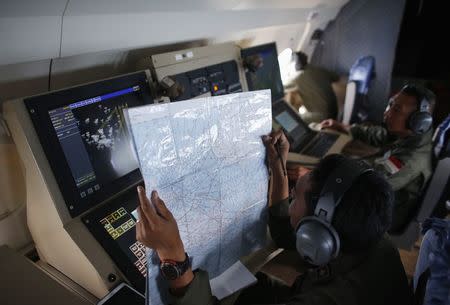 A crew member on an Indonesian Maritime Surveillance plane checks a map during a search for AirAsia's Flight QZ8501 north of Bangka island December 30, 2014. REUTERS/Darren Whiteside