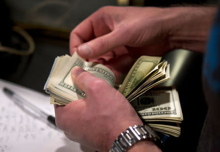 FILE PHOTO: A man counts out $100 bills as he makes a bet on Super Bowl XLVIII at the Las Vegas Hotel & Casino Superbook in Las Vegas, Nevada, U.S., January 23, 2014. REUTERS/Las Vegas Sun/Steve Marcus/File Photo