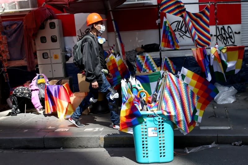 A man walks between Wiphala flags for sale in La Paz