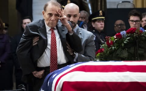 Former Senator Bob Dole stands up and salutes the casket of the late former President George HW Bush - Credit: Getty