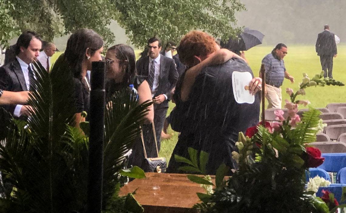 Buster Murdaugh, center, receives a hug in the pouring rain at the funeral service for his brother, Paul, and mother, Maggie, on June 11, 2021.