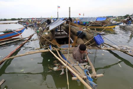 A fisherman takes a break after securing his small boat in a safer area in preparations for the strong winds brought by Typhoon Rammasun, locally name Glenda, in a coastal area of Cavite city, south of Manila July 15, 2014. REUTERS/Romeo Ranoco