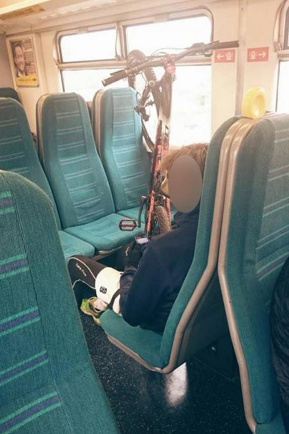 A cyclist using several train seats to store his bike