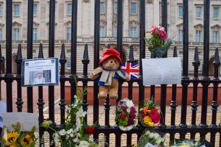 LONDON, UNITED KINGDOM - 2022/09/11: A Paddington Bear toy is seen alongside flowers and tributes outside Buckingham Palace as thousands of people continue to arrive to pay their respects to Queen Elizabeth II. The Queen died on September 8th, aged 96. (Photo by Vuk Valcic/SOPA Images/LightRocket via Getty Images)