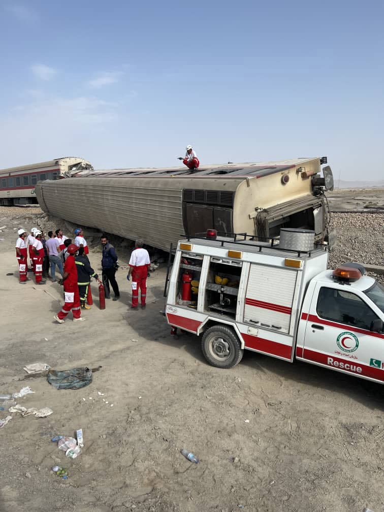 In this photo provided by the Iranian Red Crescent Society, rescuers work at the scene where a passenger train partially derailed near the desert city of Tabas in eastern Iran, Wednesday, Iran, Wednesday, June 8, 2022. (Iranian Red Crescent Society via AP)