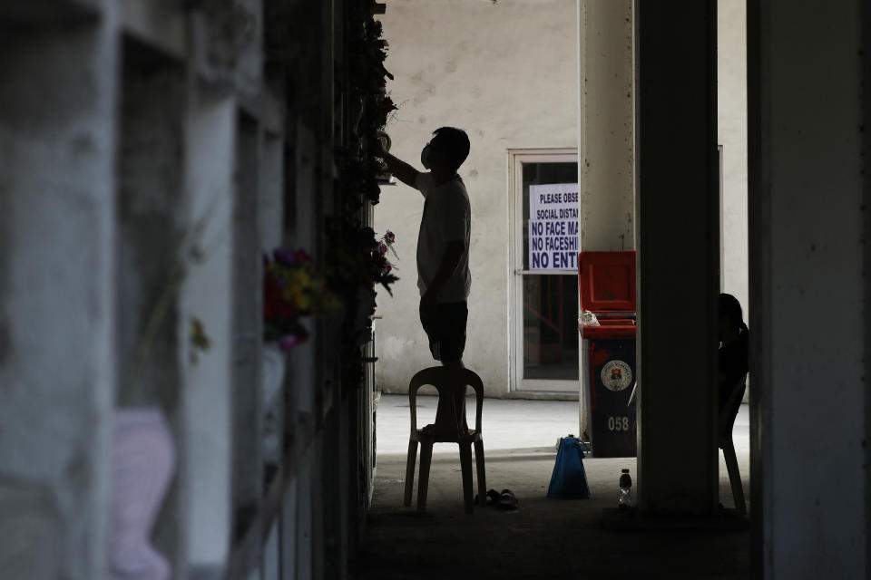 A man wearing a facemask to prevent the spread of the coronavirus cleans a tomb of a relative at Manila's North Cemetery, Wednesday, Oct. 28, 2020, in Manila, Philippines. The government has ordered all private and public cemeteries, memorial parks, and columbariums to be closed from Oct. 29 to Nov. 4, 2020, to prevent people from gathering during the observance of the traditionally crowded All Saints Day and to help curb the spread of the coronavirus. (AP Photo/Aaron Favila)