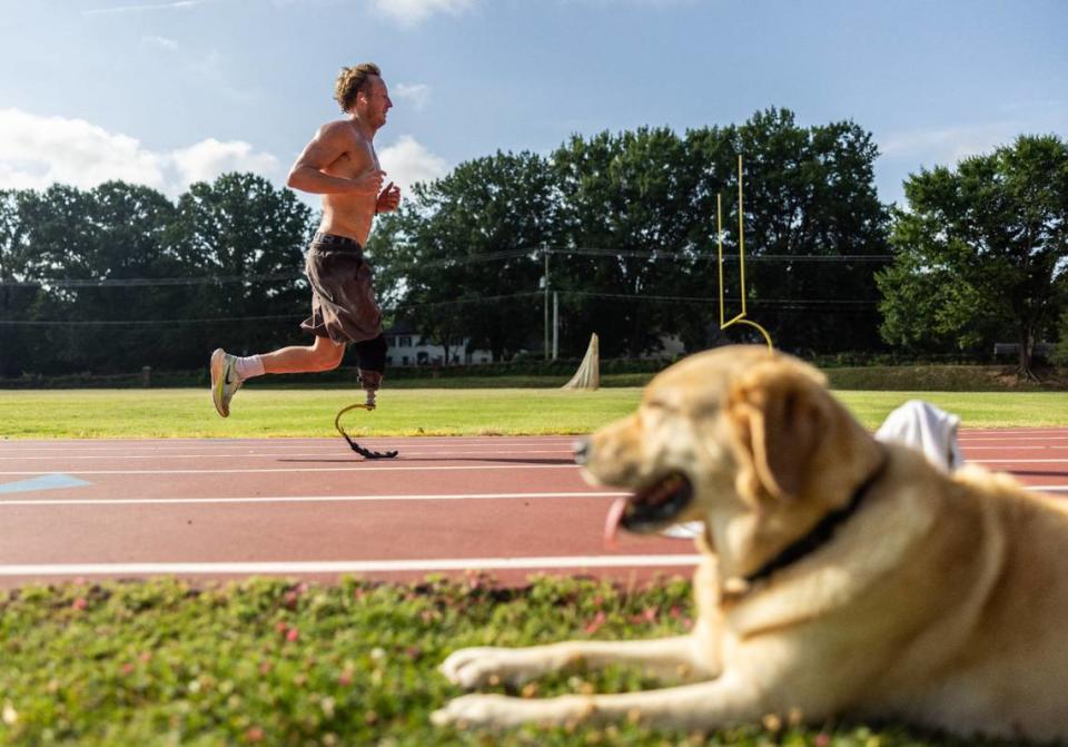 Carson Clough trains for the Paralympics triathlon while his service dog, Calder, keeps an eye on him at Alexander Graham Middle School in Charlotte, N.C., on Saturday, July 6, 2024.