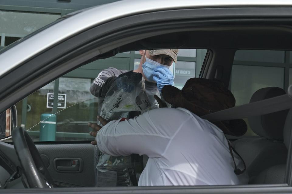 An employee brings a customer’s order to his car at Dick’s Sporting Goods in Paramus, N.J., in May 2020. (AP Photo/Seth Wenig)