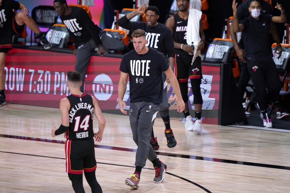 Miami Heat's Meyers Leonard, center, runs onto the court during a time out to celebrate with Tyler Herro (14) after Herro's 3-point basket against the Boston Celtics in the first half of an NBA conference final playoff basketball game, Saturday, Sept. 19, 2020, in Lake Buena Vista, Fla. (AP Photo/Mark J. Terrill)