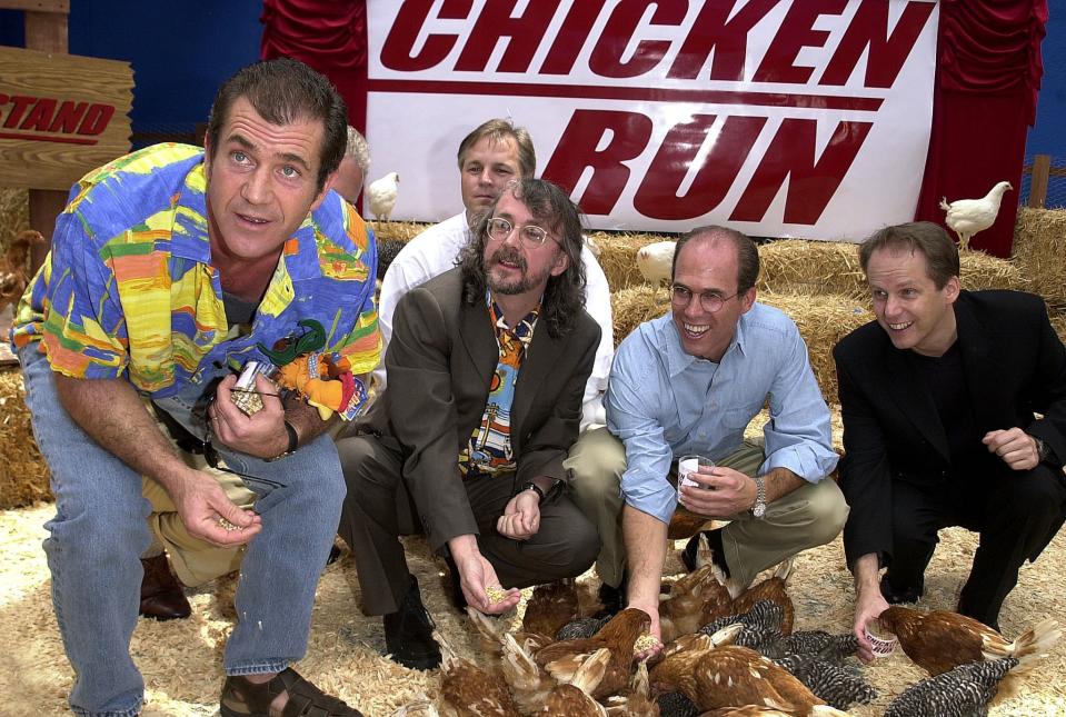 UNIVERSAL CITY, UNITED STATES:  US actor Mel Gibson (L) feeds chickens at the premiere of new British animated film "Chicken Run" for which he provides the voice of Rocky the rooster, as British directors Peter Lord (2nd L) and Nick Park (R), and executive producer Jeffrey Katzenberg (2nd R) look on, in Universal City, CA 17 June, 2000.   (ELECTRONIC IMAGE)   AFP PHOTO/Lucy NICHOLSON (Photo credit should read LUCY NICHOLSON/AFP via Getty Images)