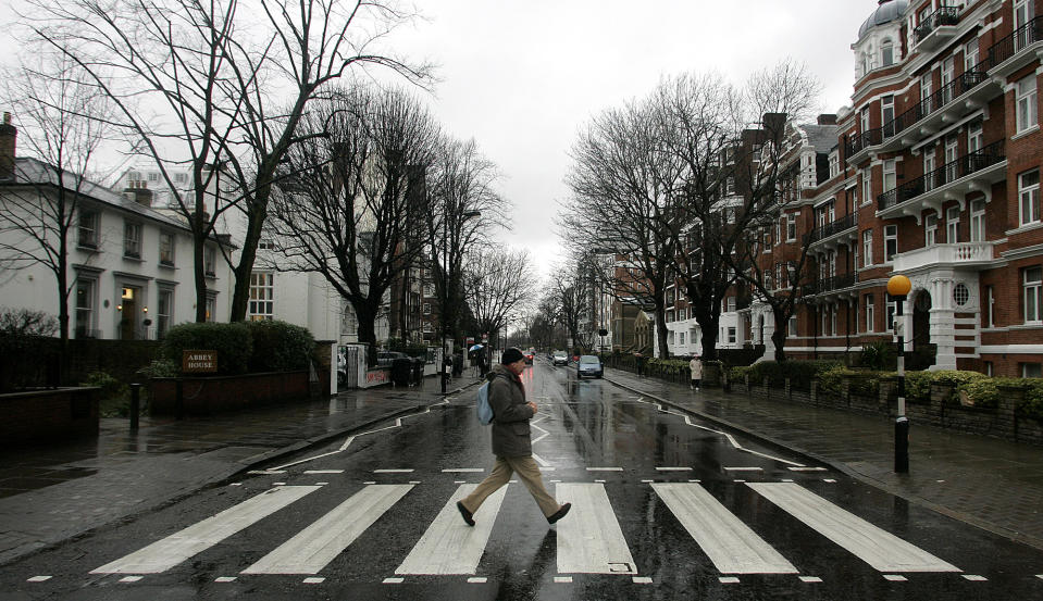 FILE - In this file photo taken Feb. 16, 2010, a man walks on the zebra crossing made famous from the album cover of The Beatles' "Abbey Road" in front of Abbey Road Studios, seen at left, in London. London counts at least 11 Abbey Roads, with potential tourist pitfalls in neighborhoods such as Barking or Bexleyheath, both of which are on the outer edges of central London. In the British capital, as elsewhere, the common street name harkens back to the medieval priories that once dotted the area. (AP Photo/Akira Suemori, File)