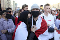 A couple wearing face masks to protect against coronavirus and covered themselves by an old Belarusian flag stand in front of police blocking the road to prevent against an opposition rally to protest the official presidential election results in Minsk, Belarus, Sunday, Sept. 20, 2020. Tens of thousands of Belarusians calling for the authoritarian president to resign marched through the capital on Sunday as the country's wave of protests entered its seventh week. Hundreds of soldiers blocked off the center of Minsk, deploying water cannon and armored personnel carriers and erecting barbed wire barriers. (AP Photo/TUT.by)