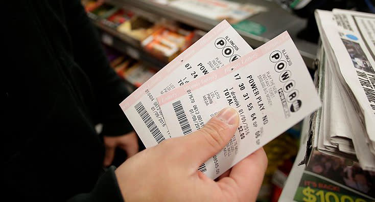 A file image of a man holding two Powerball tickets in his hand at a store.