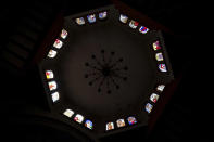 Sunlight illuminates the stained-glass windows of the Espiritu Santo church in the Puerpecha Indigenous community of Comachuen, Wednesday, Jan. 19, 2022. Many things in Comachuen, the church, the bull ring, the charity donations, are paid for by migrants with money they made working in the United States. Many get H2A temporary U.S. work visas; others go without documents. (AP Photo/Fernando Llano)