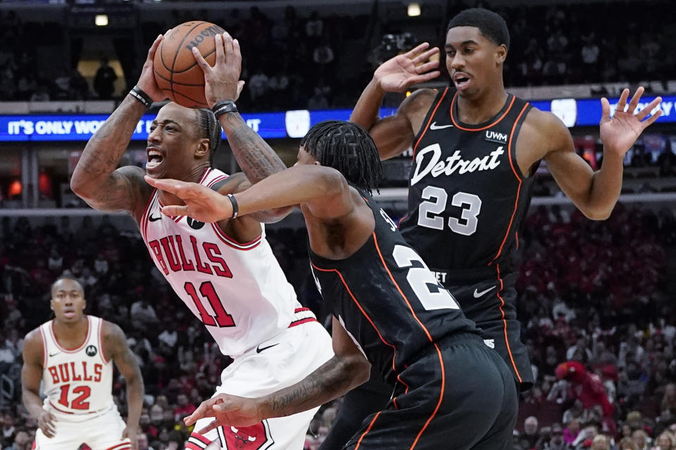 Chicago Bulls forward DeMar DeRozan, left, drives to the basket past Detroit Pistons guard Marcus Sasser and guard Jaden Ivey, right, during the first half of an NBA basketball game in Chicago, Sunday, Nov. 12, 2023. (AP Photo/Nam Y. Huh)