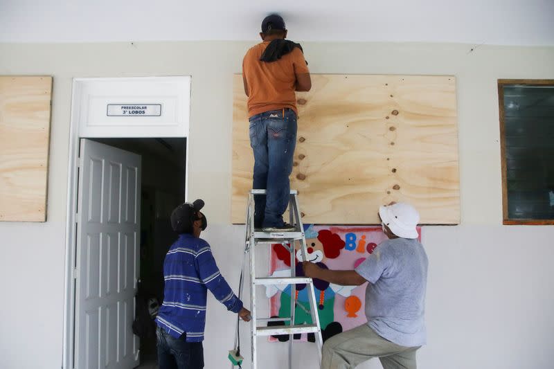 Workers board up the windows of a classroom at a school that will be used as a temporary shelter for tourists, in preparation for the arrival of Hurricane Delta, in Cancun