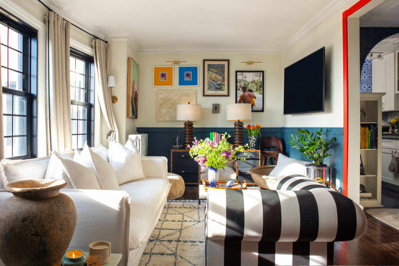 white living room with teal wainscoting, white sofa, black and white striped chair, and large windows