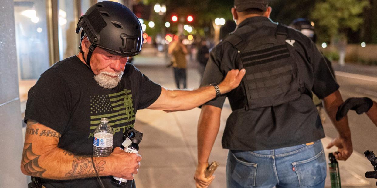 proud boy jeffrey grace pepper sprayed holding onto man with back turned to the camera