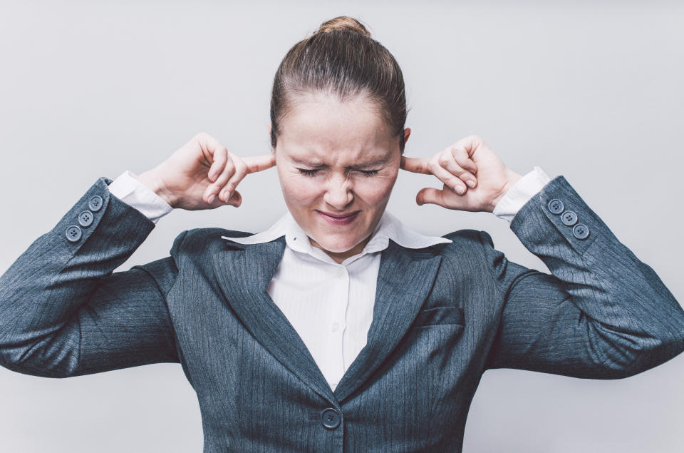 Businesswoman putting finger in ears.