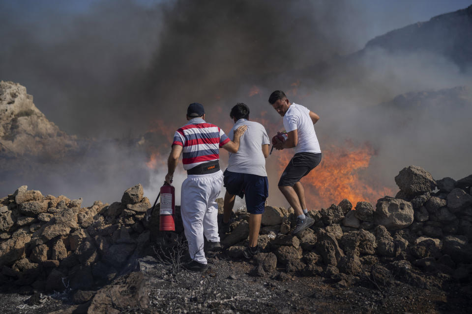 ARCHIVO - Vecinos intentan extinguir un incendio cerca del balneario de Lindos, en la isla griega de Rodas en el mar Egeo, 24 de julio de 2023. (AP Foto/Petros Giannakouris, File)
