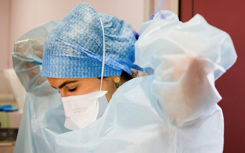 A health worker puts on personal protective equipment (PPE) in the intensive care unit (ICU) at the Ambroise Pare Clinic in Paris - Bloomberg