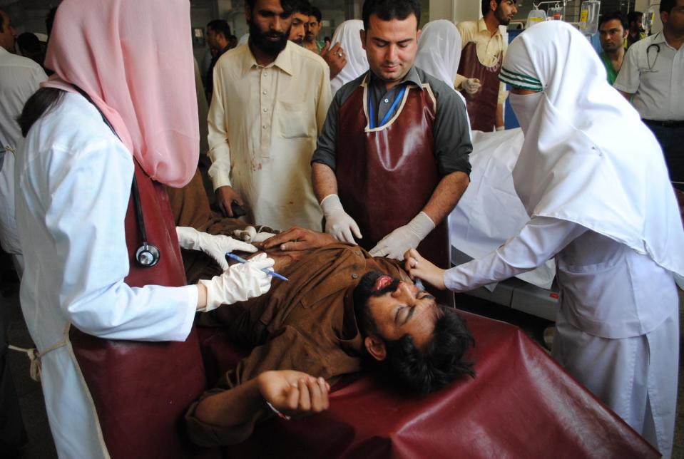 Hospital staff treat a victim of a blast at a local hospital in Peshawar, Pakistan, Tuesday, April 22, 2014. Two militant attacks in northwestern Pakistan killed many people, including five policemen, on Tuesday, officials said. The Pakistani government has been trying to negotiate a peace deal with the Taliban in efforts to end years of fighting in the northwest that has killed thousands of people. (AP Photo/Mohammad Sajjad)