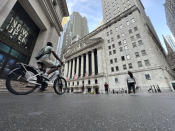 A bike rider approaches the New York Stock Exchange, rear, on Tuesday, July 9, 2024, in New York. Global shares are mostly higher, with Japan's benchmark Nikkei 225 jumping 2% to finish at another record high. (AP Photo/Peter Morgan)