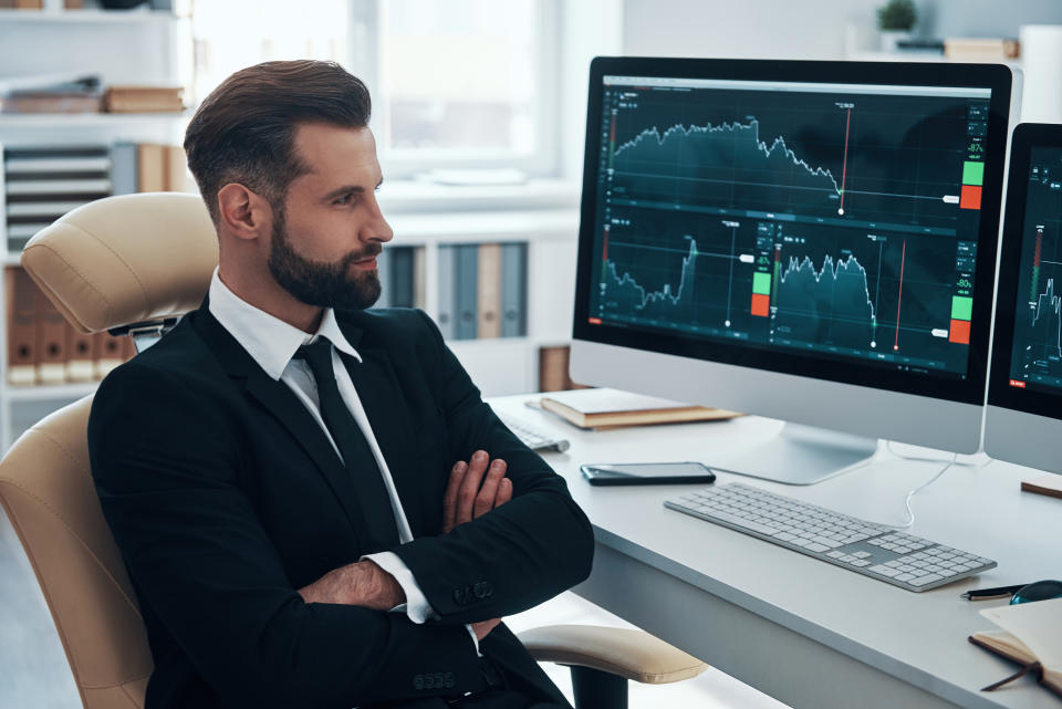 Thoughtful young man in shirt and tie analyzing data on the stock market while working in the office