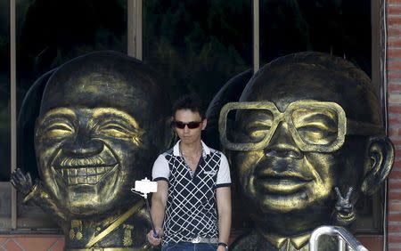 A man takes a selfie between figurines depicting Nationalist leader Chiang Kai-shek (L) and his son, Chiang Ching-kuo, in Taoyuan, nothern Taiwan, July 5, 2015. REUTERS/Pichi Chuang