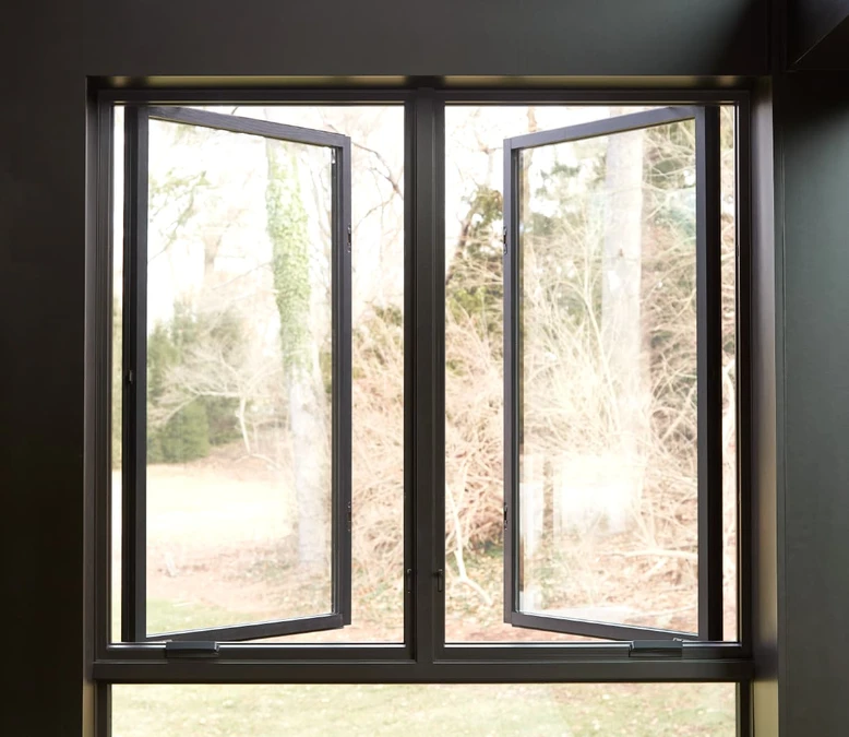 Two black casement windows open outward on a sunny yard.